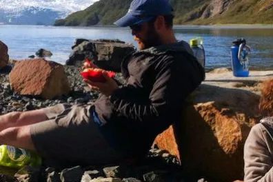 a person sitting on a rock next to a body of water