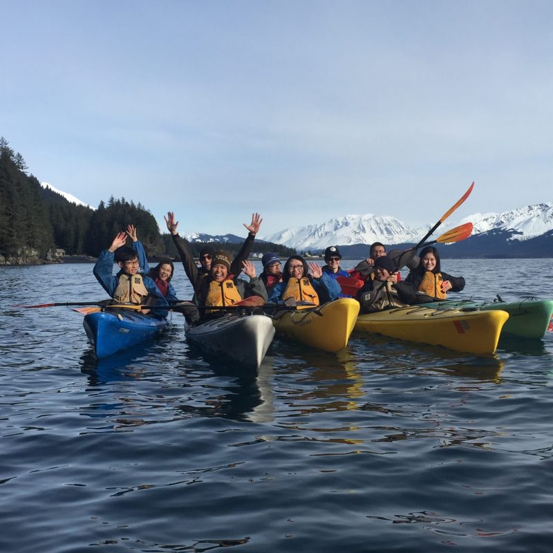 a group of people riding on the back of a boat in the water