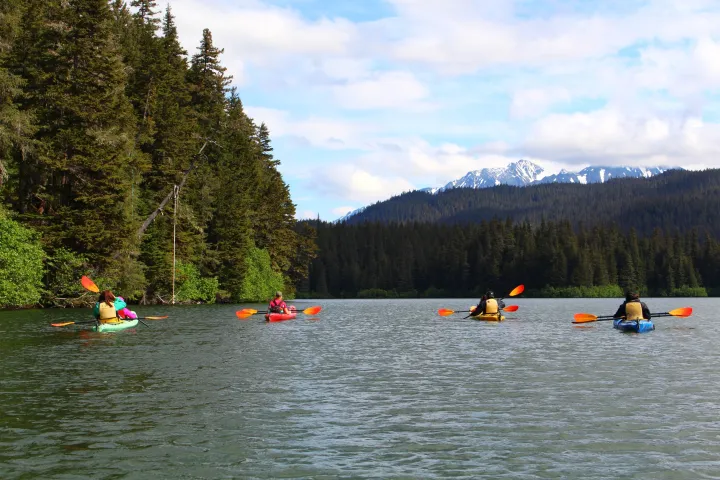 a group of people rowing a boat floating on top of a lake
