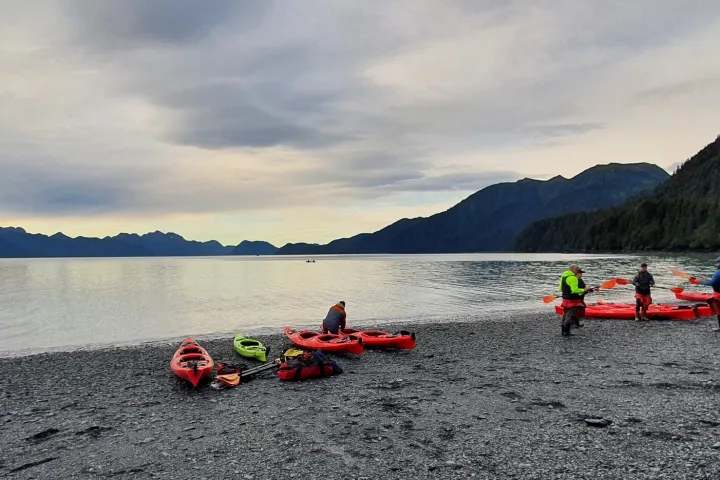 a group of people on a beach near a body of water with Lake Wenatchee State Park in the background