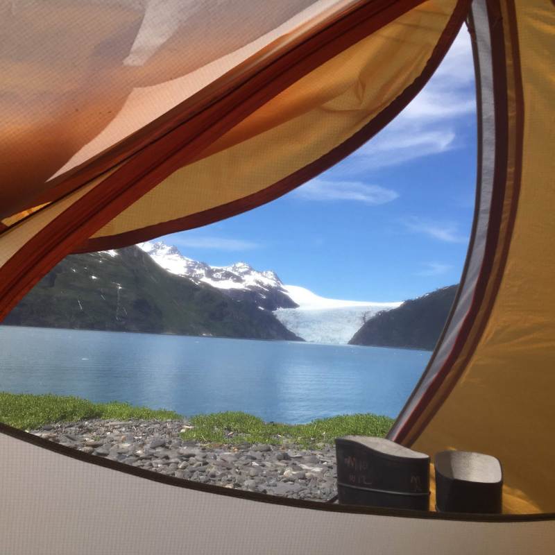 View of lake and snowy mountain through a tent opening.