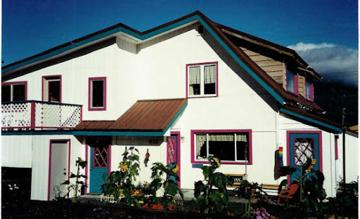 Colorful two-story house with purple trim and sunflowers in the garden.